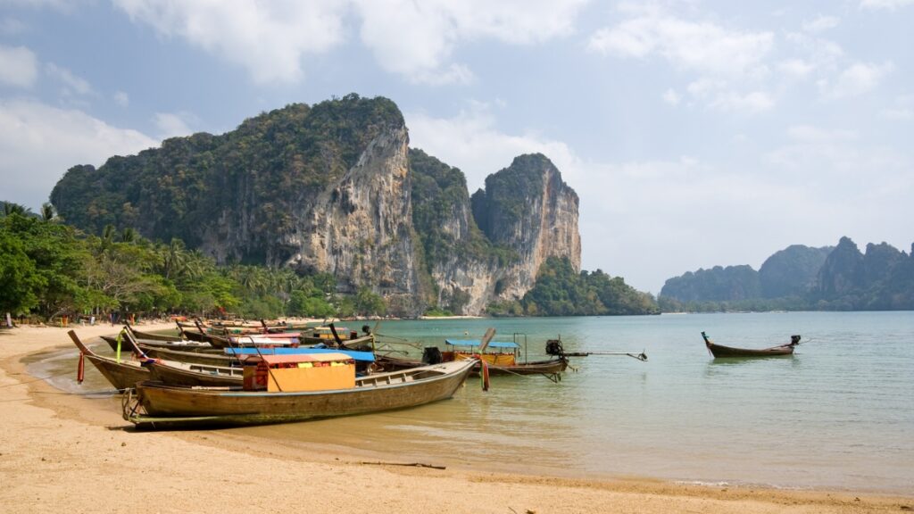 Longtail boats docked at Tonsai Beach, Krabi, Thailand, with limestone karsts in the distance